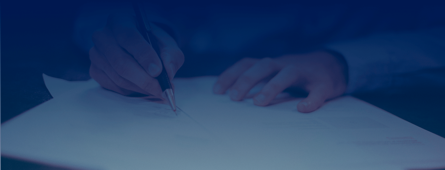 Persona firmando un documento con bolígrafo sobre una mesa