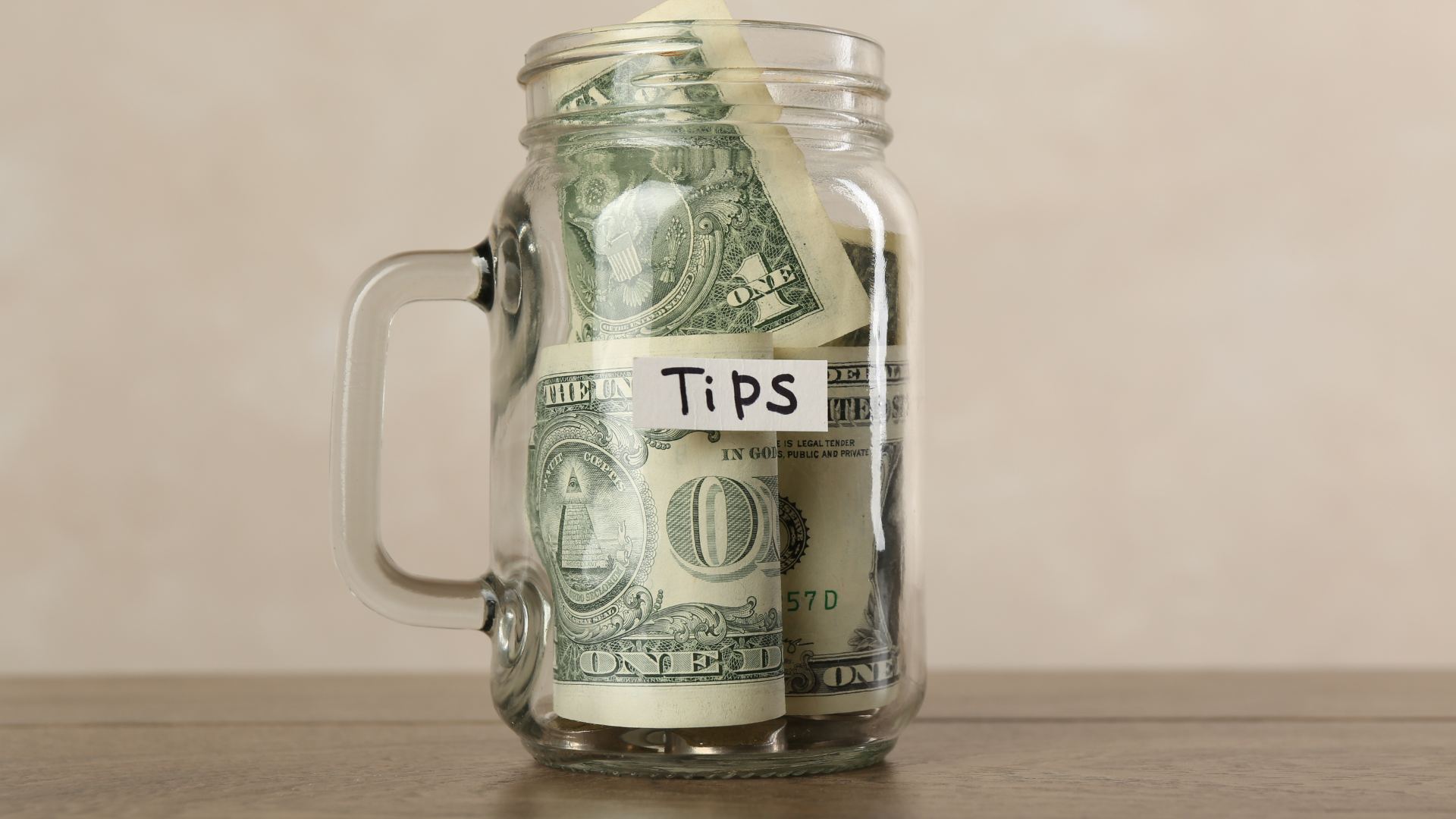 Tarro de cristal con dólares estadounidenses y la etiqueta "Tips", símbolo de la cultura de la propina en Estados Unidos.